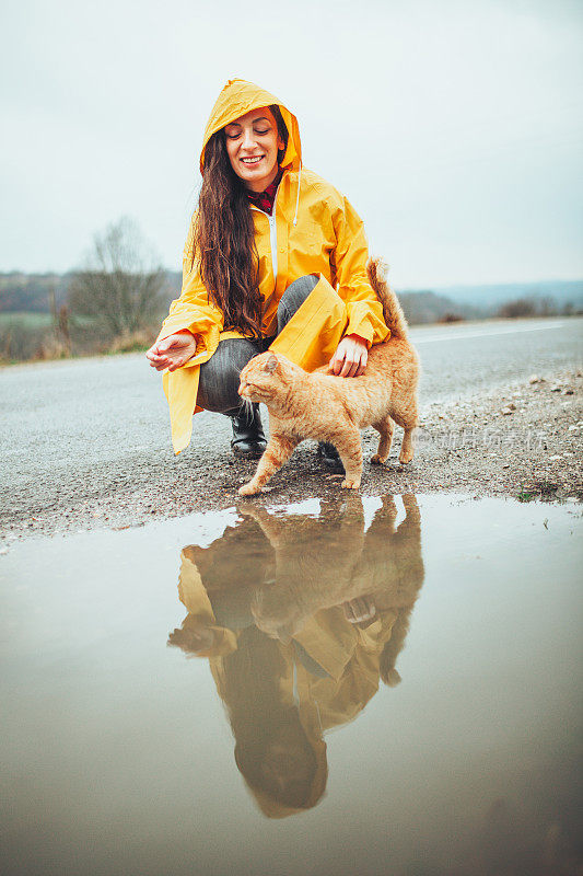 快乐的女孩和猫在大自然的雨