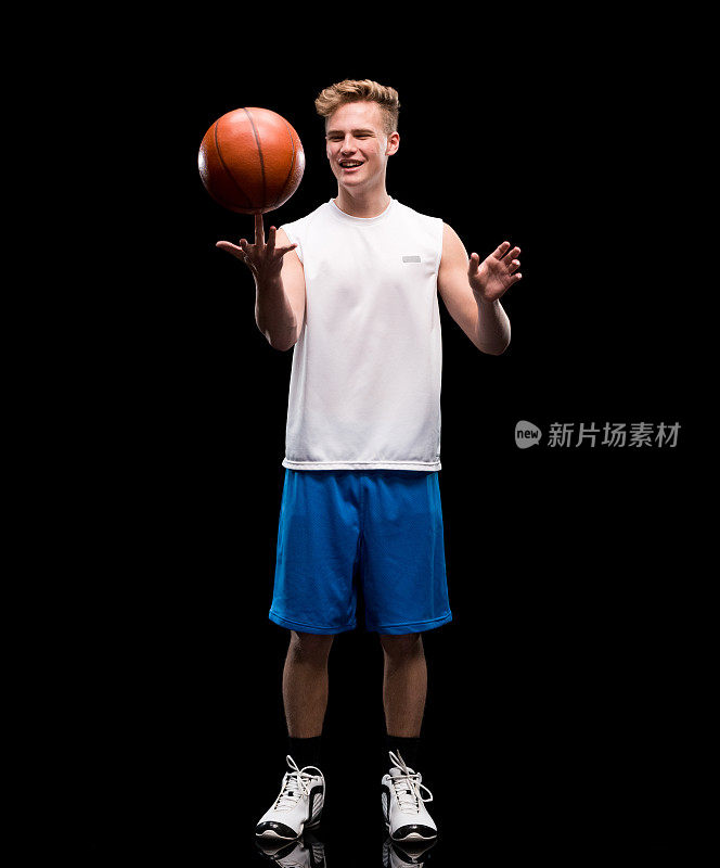 白人男性无袖站在黑色背景前，穿着短裤，拿着篮球，用运动球