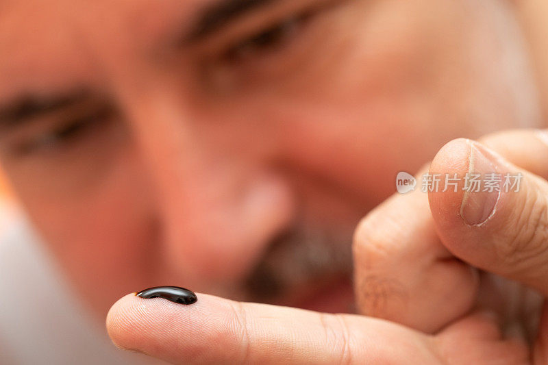 成熟的男人看着大麻树脂在他的手指上的特写
