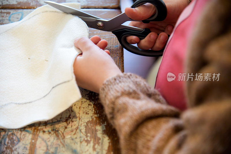 孩子和工艺品。特写的小女孩的手切割一个猫形状的布面具