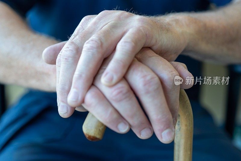 老人双手拄着拐杖。一位拄着拐杖的老人。老人拄着一根老拐杖支撑着自己。残疾意识。拄着拐杖的老妇人。老妇人手里拿着手杖。