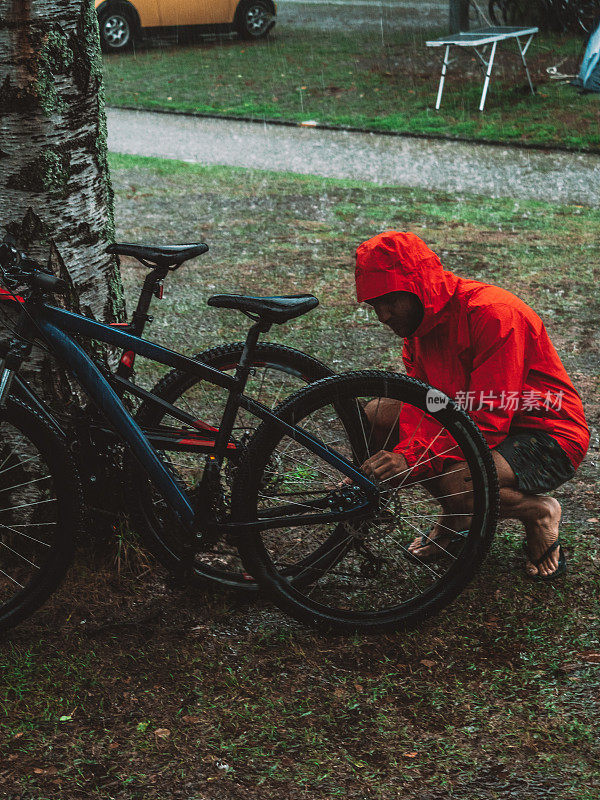 一名男子在暴雨中修理山地车