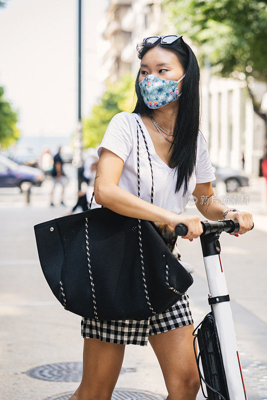 年轻女子戴着防护面罩，骑着电动车在城市中穿行