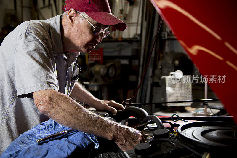 年长的白人机械师检查越野车的马达。