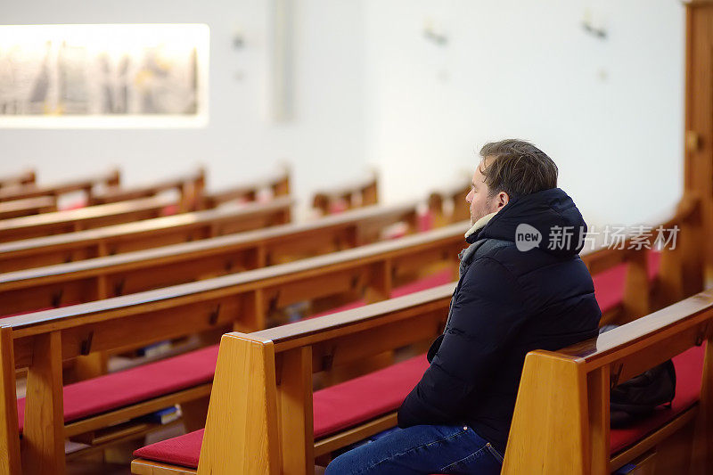 宗教的中年男子在天主教教堂祈祷。人们闭上眼睛，祈求上帝的宽恕和祝福。