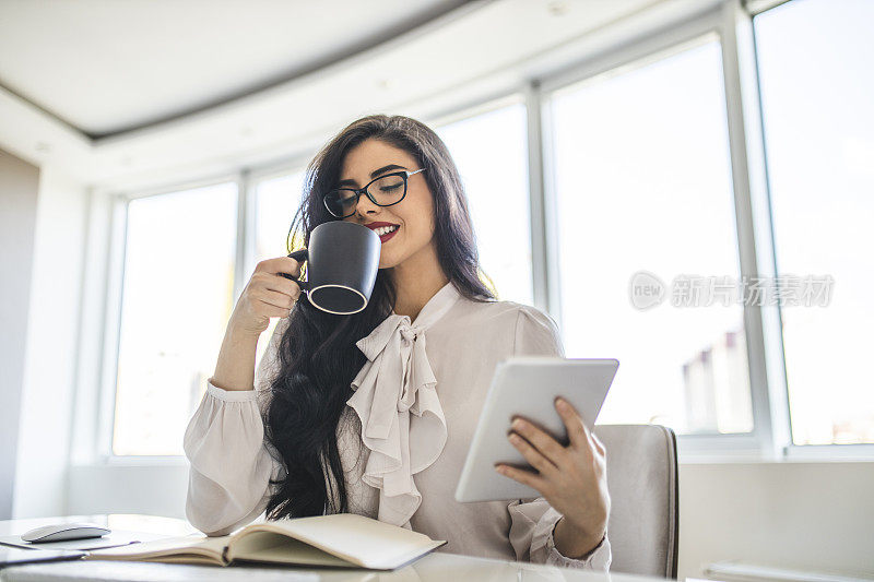 女商人休息，喝咖啡，在办公室里用平板电脑