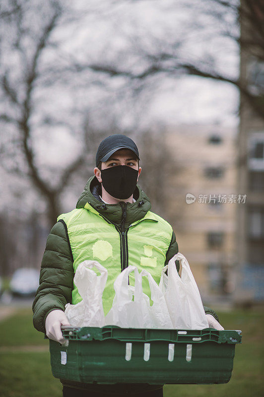 年轻的送货员戴着防护面具和防护手套