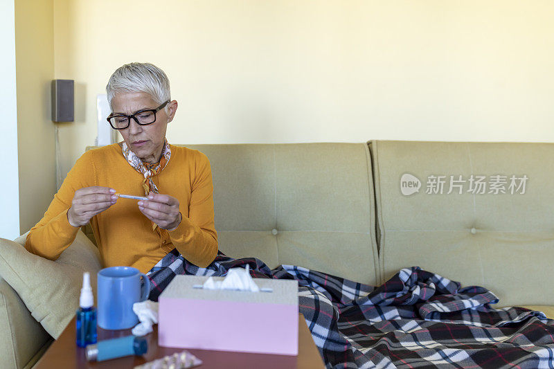 一个年长妇女在床上的肖像，盖着毯子由于高温。