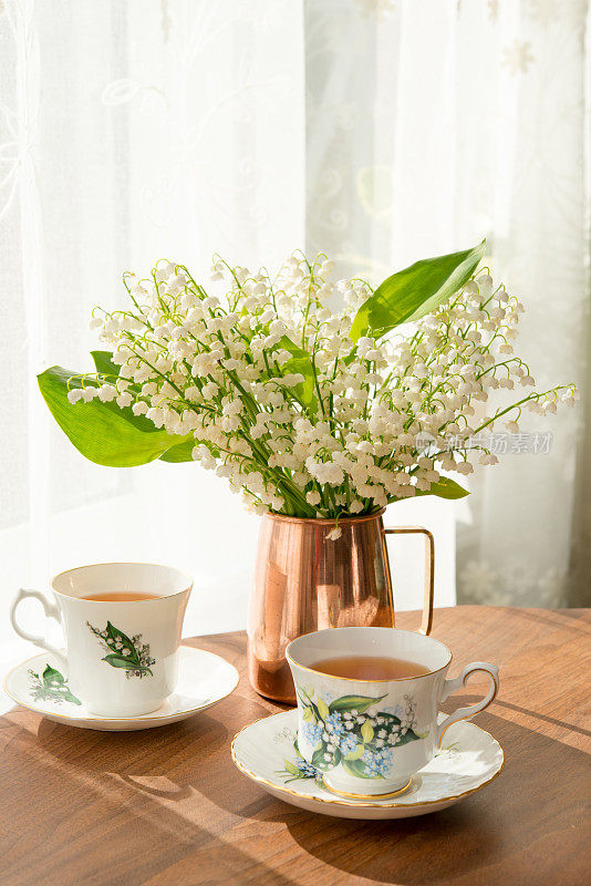 古铜色花瓶里的铃兰花束，配上配套的茶杯