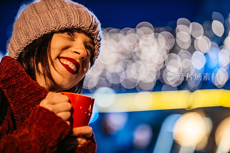 美丽的女人在圣诞节晚上在户外喝茶