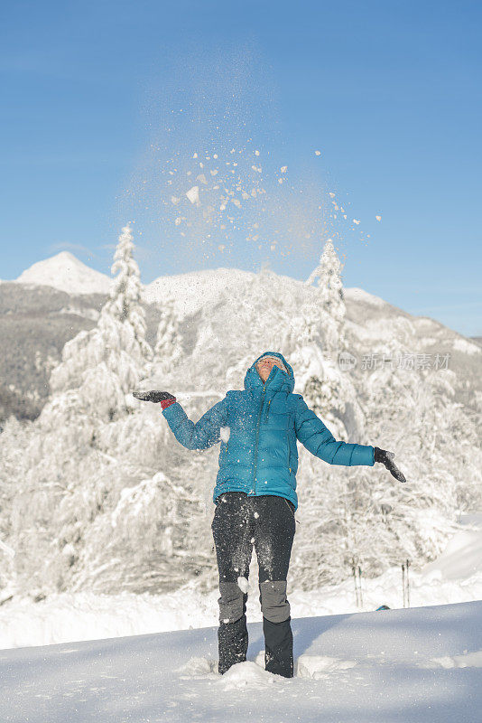 在冬天的森林里，成熟的女人穿着皮大衣向空中抛雪