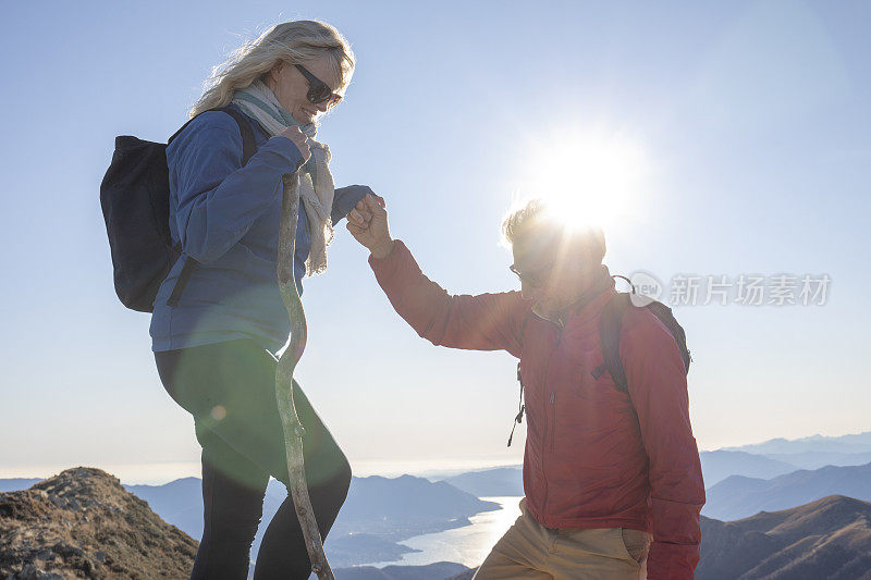 成熟的夫妇徒步爬上阳光灿烂的山脊