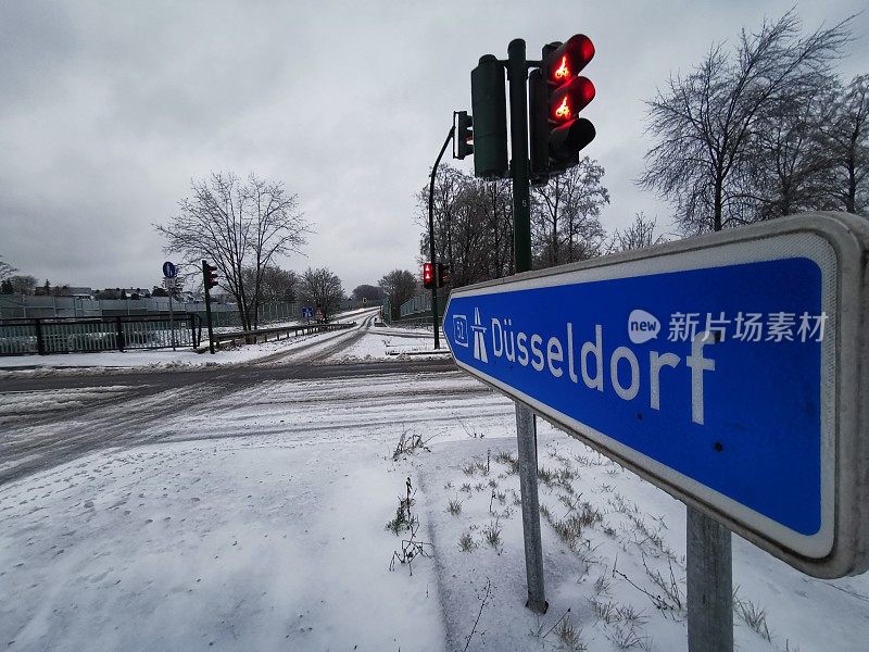 在北莱茵-威斯特法伦埃森一个罕见的下雪的早晨，杜塞尔多夫高速公路的标志和红色交通灯