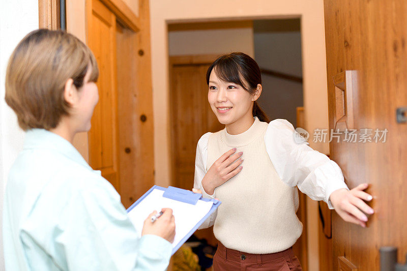 一名年轻的亚洲女性在入口处与一名女员工交谈
