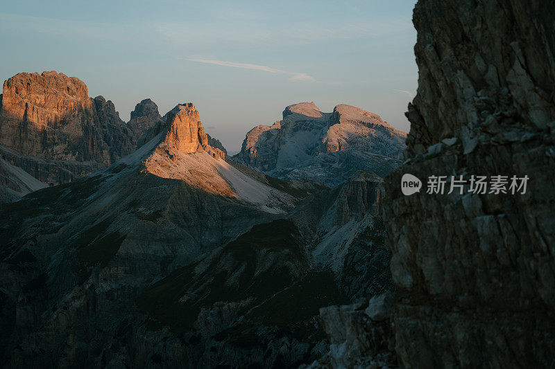 黄昏时分，蓝天下陡峭的悬崖和山峰的宁静景色。下面是绿色的山谷。特伦蒂诺山谷完美的徒步度假胜地