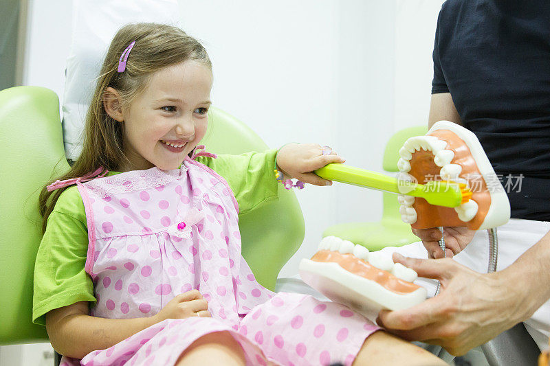 女孩在牙医的椅子上刷牙，一个模特