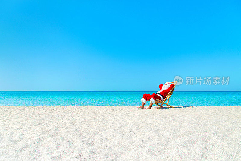 圣诞老人在海洋沙滩上的躺椅上休息