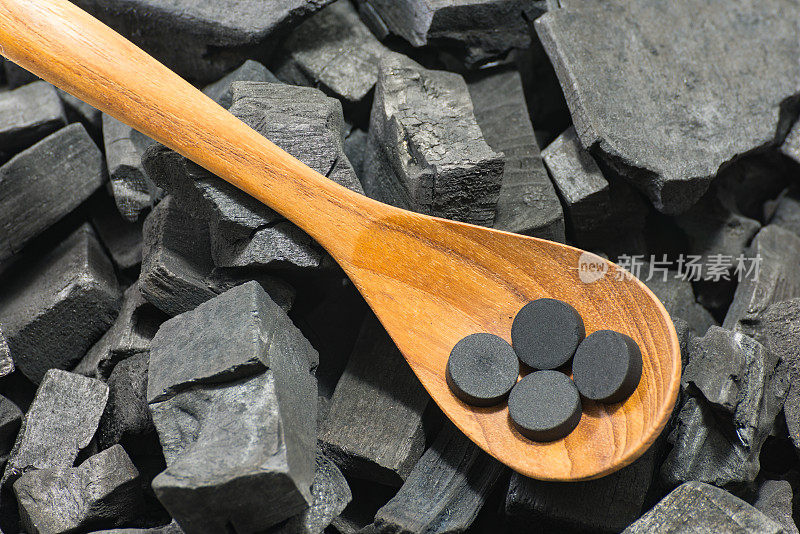 活性炭丸在木勺上以木炭为纹理背景