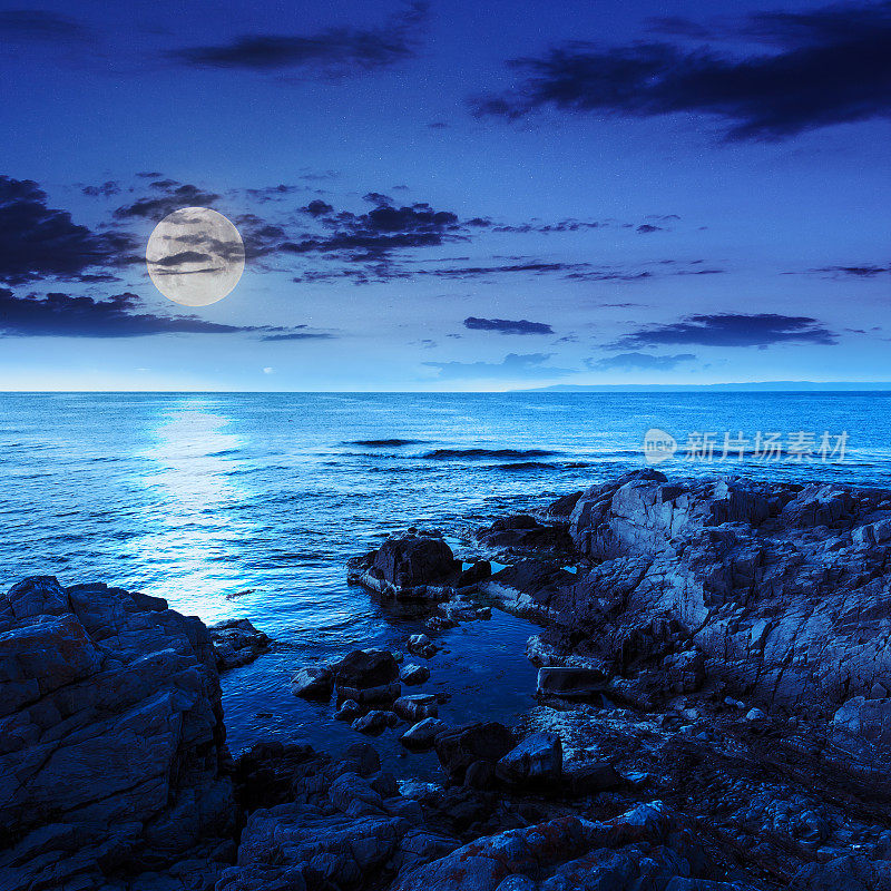 夜晚海面平静，岸边有巨石