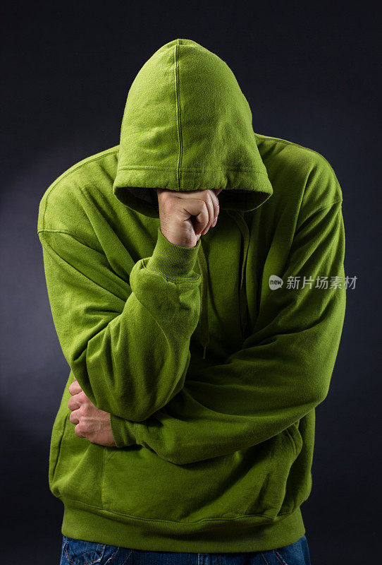 穿着绿色连帽衬衫的男性，头上有拳头