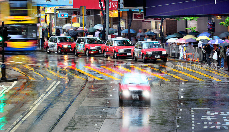 香港街道在雨中，的士、巴士、行人、雨伞