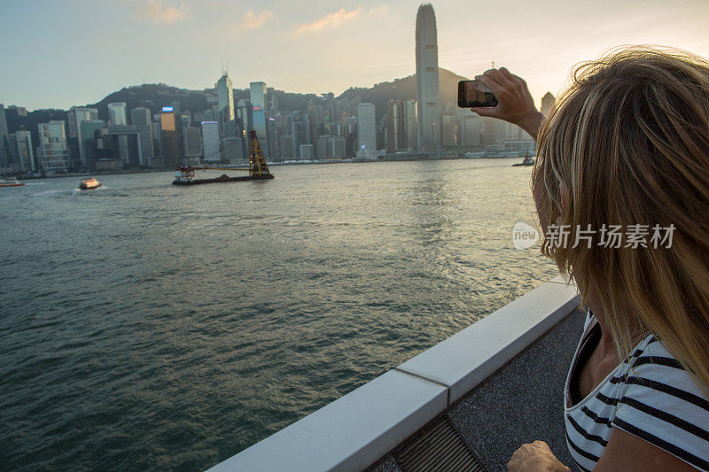 一名年轻女子在香港用手机拍摄日落