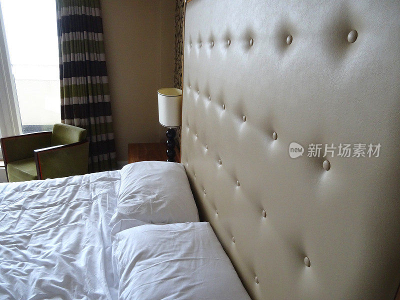 大双人床，米色绣花皮革床头板，白色床单，床头灯