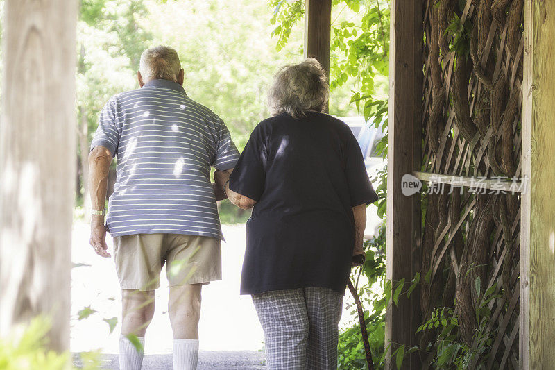 一对老年夫妇在自然公园的棚架下散步
