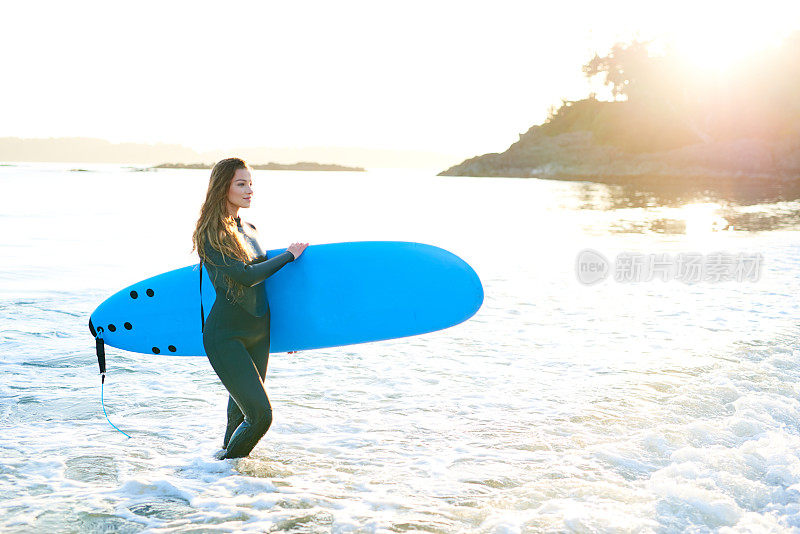 强壮美丽的年轻女人在海滩上冲浪