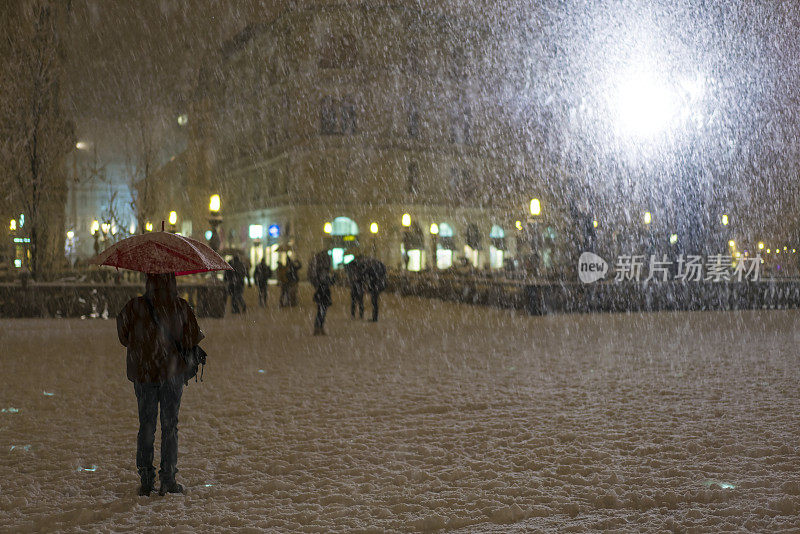 斯洛文尼亚Presern广场上飘落的伞和雪。