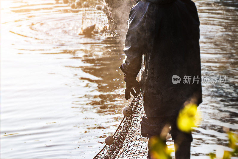 在法国的多姆斯池塘里用大渔网捕鱼的渔夫