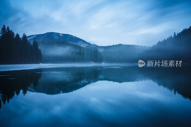 湖被山和森林包围的黄昏