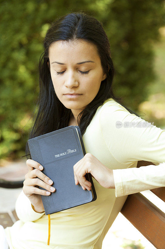手持圣经祈祷的年轻女子
