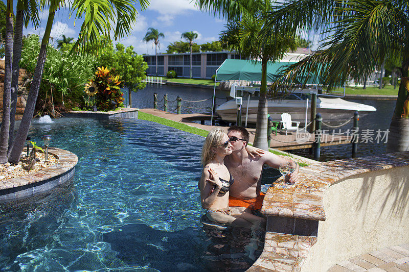 浪漫的情侣在豪华热带泳池放松