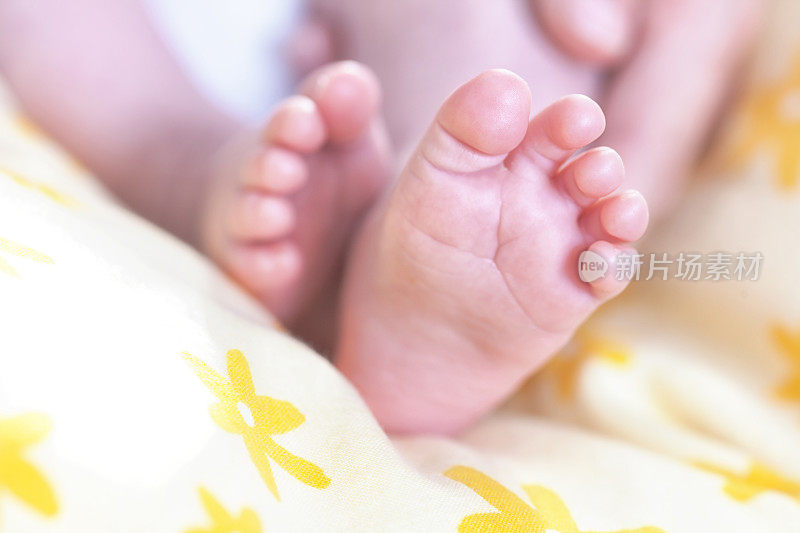 初生婴儿的脚放在黄色的毯子上