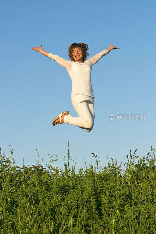 一位白衣女子在草地上跳跃