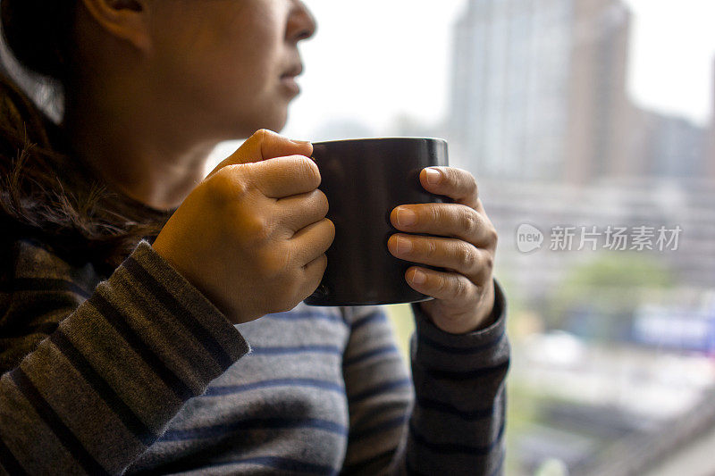 拿着咖啡杯的女孩，坐在窗边