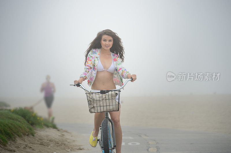 年轻女子骑着自行车，清晨有雾