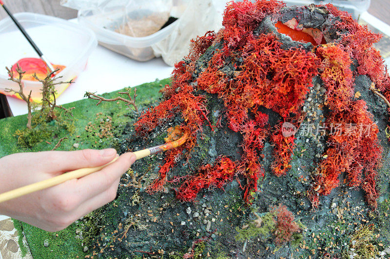 女孩画火山模型的图像，为学校项目制作