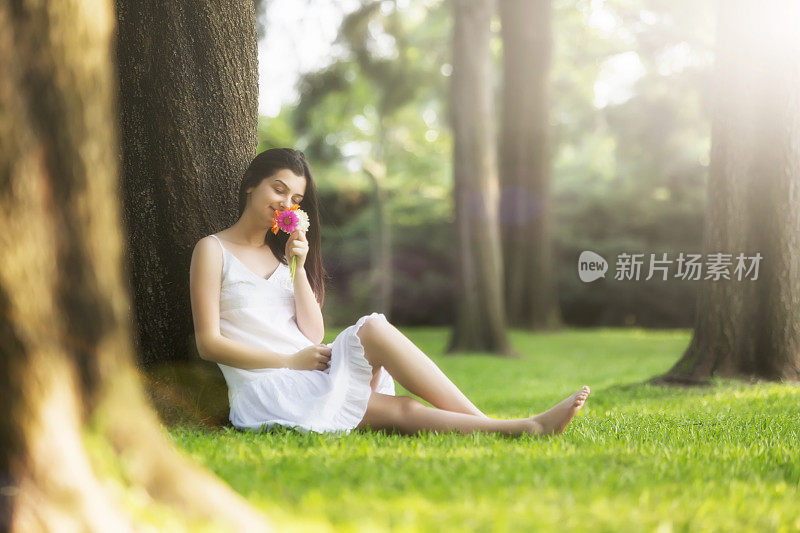 美丽的女孩，在阳光明媚的日子闻着非洲菊花