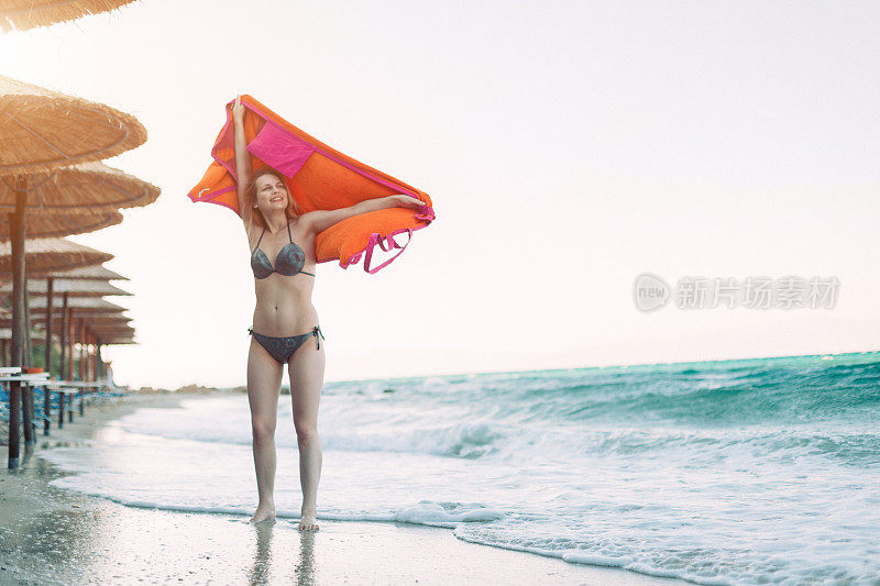 一个在海滩上拿着毛巾的快乐年轻女人