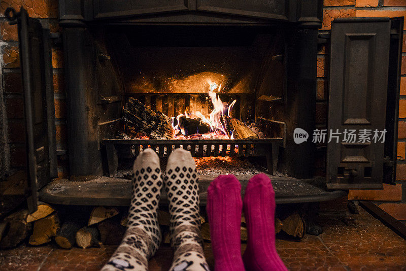 脚上穿着羊毛袜子，在温暖的炉火旁取暖