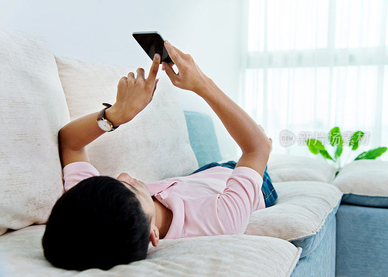 年轻人在沙发上玩智能手机