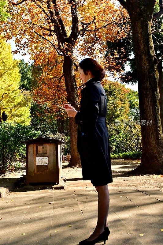 一名日本妇女在东京的公园里查看手机邮件
