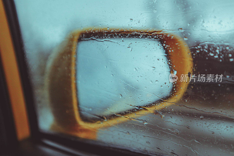 黄色汽车后视镜与道路反射，雨天天气。