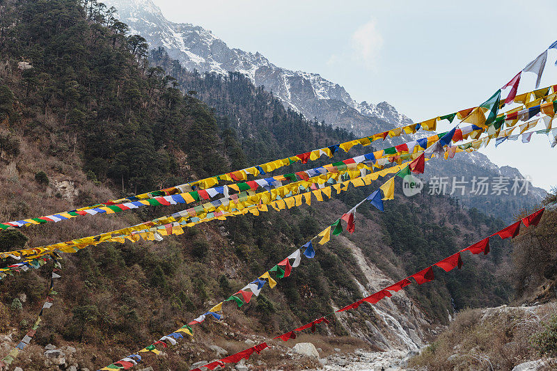 在冬季拉钦的坦古和乔普塔山谷，西藏经幡和山顶积雪的黑山是背景。北锡金,印度。