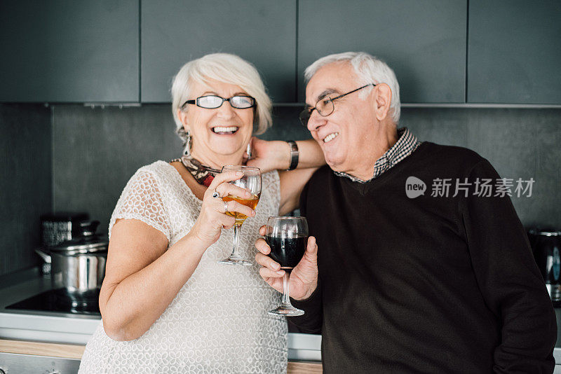 快乐的老夫妇在厨房享用一杯优质葡萄酒