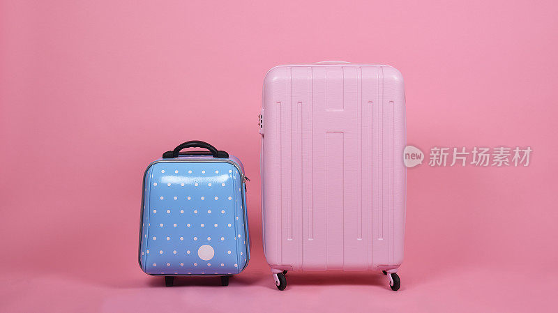 一套行李手提箱，旅行者粉红色手提箱和蓝色机舱大小的行李在粉红色的背景，旅行和旅行的概念。