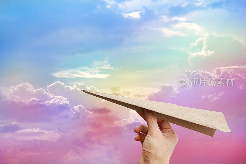 棕色的飞机火箭纸在彩色云彩天空的背景。