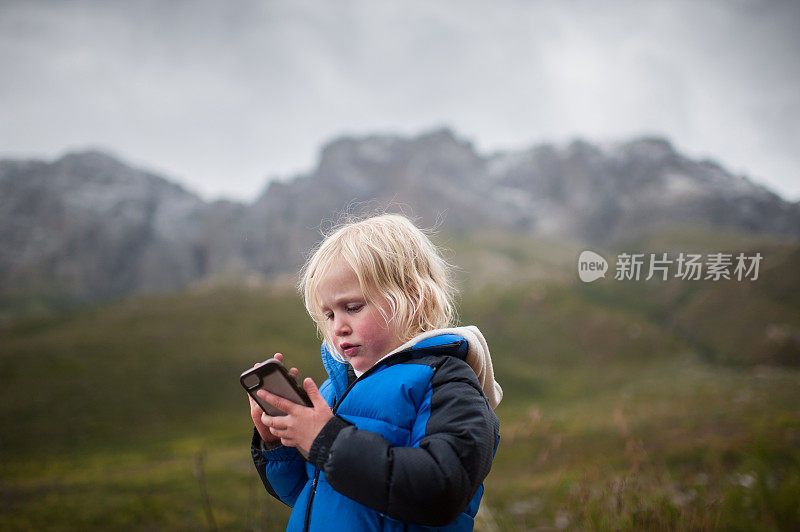 蹒跚学步的小女孩在大自然中玩智能手机